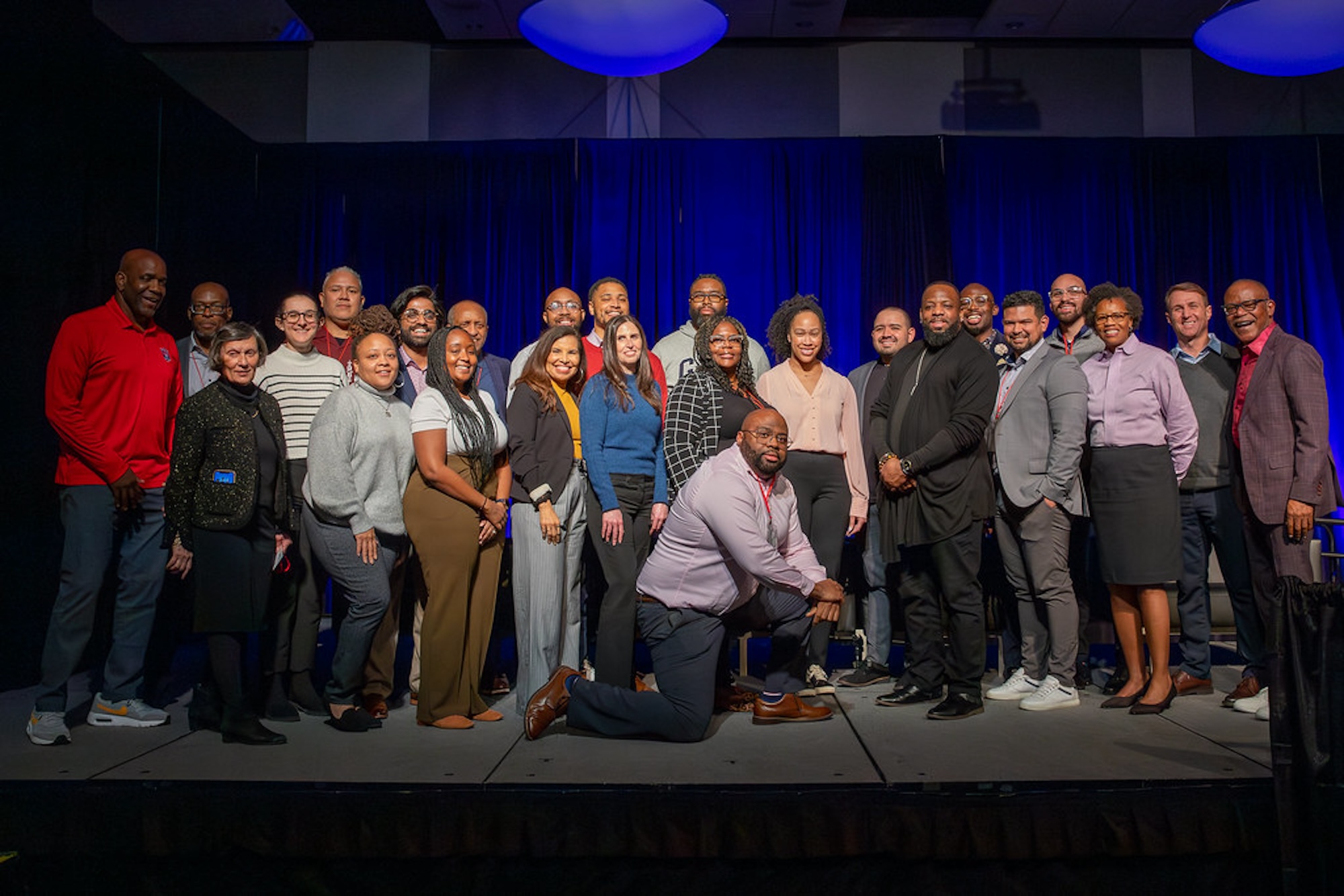 A group of people stand on stage as they all pose for a photo.