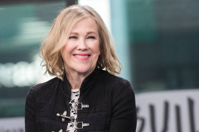 A woman with blonde hair in a dark top smiles, looking to the right