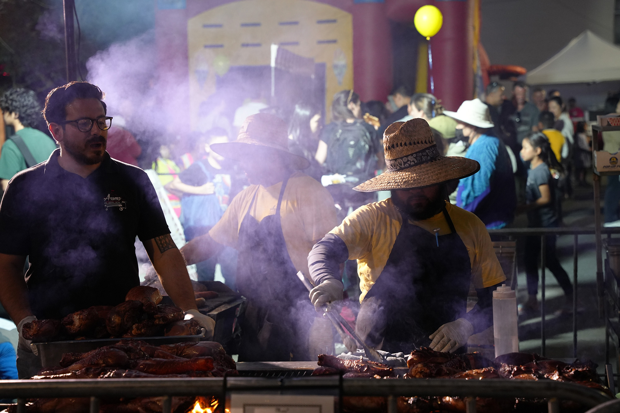 A night market vendor grills turkey legs.