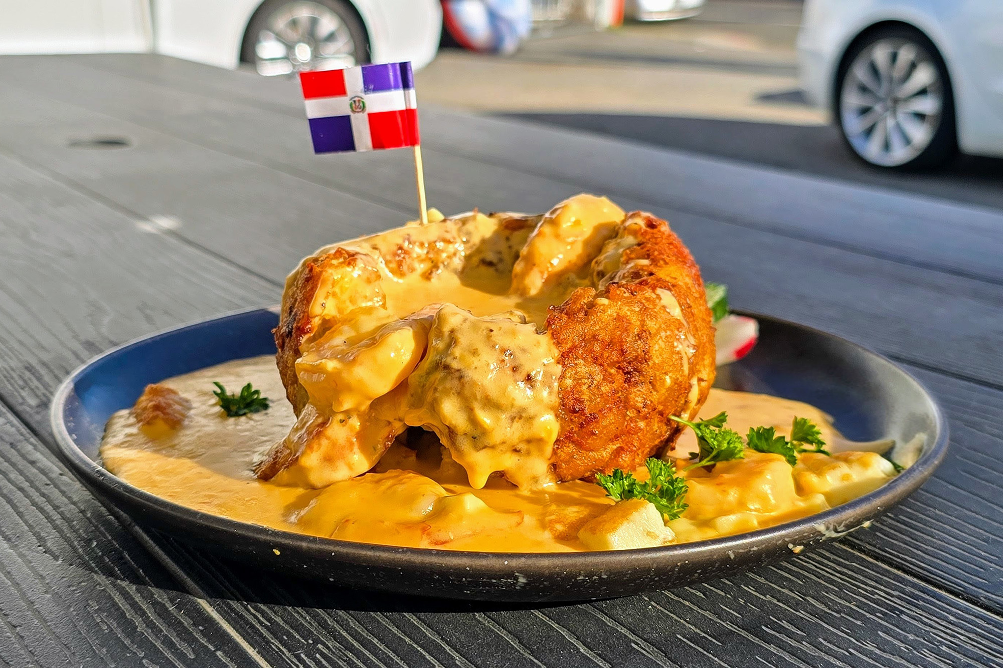 Mofongo (mashed fried plantains) covered in a creamy sauce, with a miniature Dominican flag as a decoration.