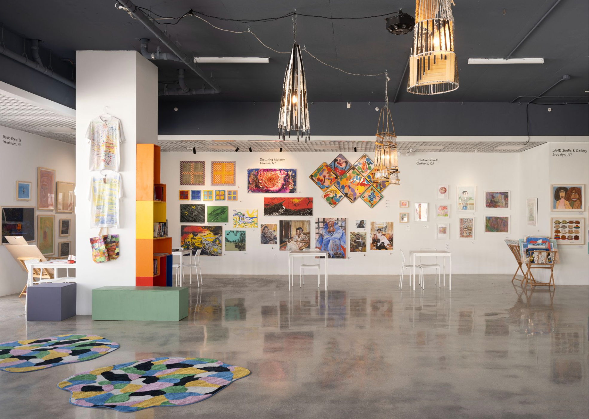 gallery view with many multicolored paintings, sculptures, t-shirts and rugs