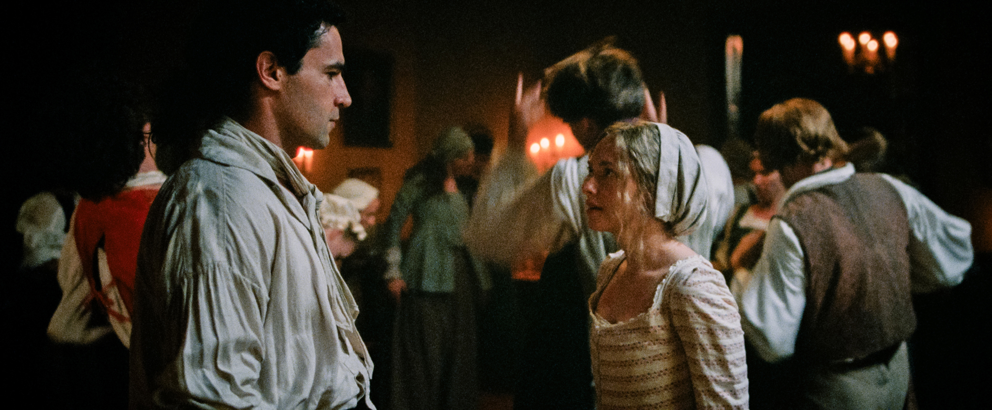 man and woman face each other in room of people