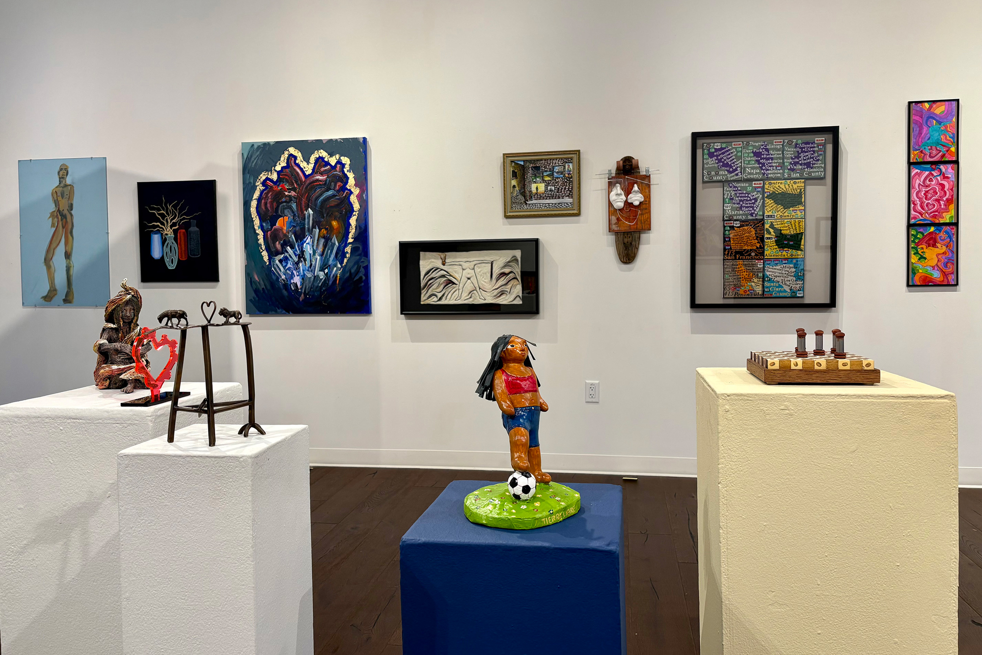 pedestals with small sculptures and salon-style hanging of wall works behind