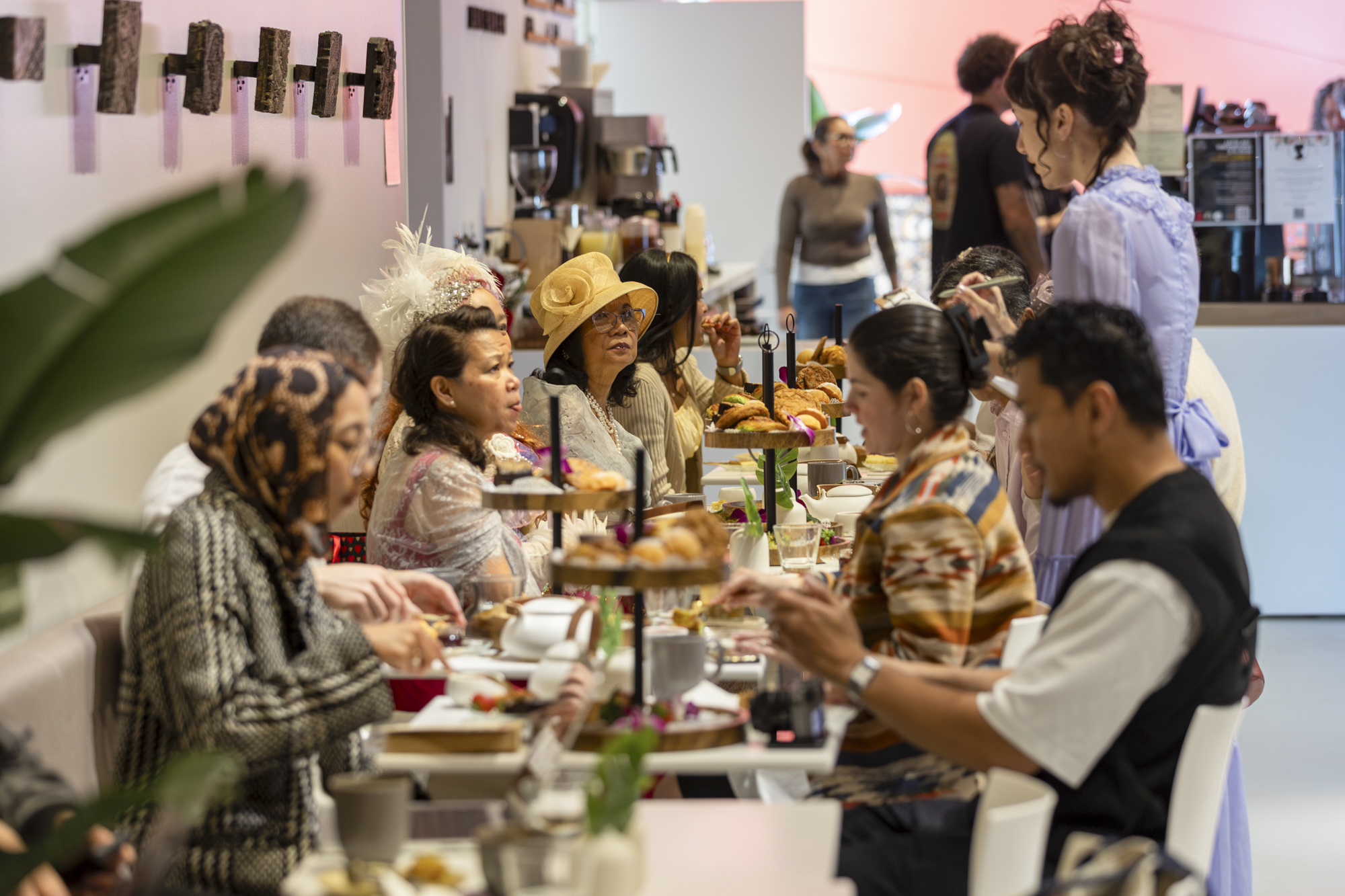 Diners enjoying an afternoon tea spread inside a busy cafe.