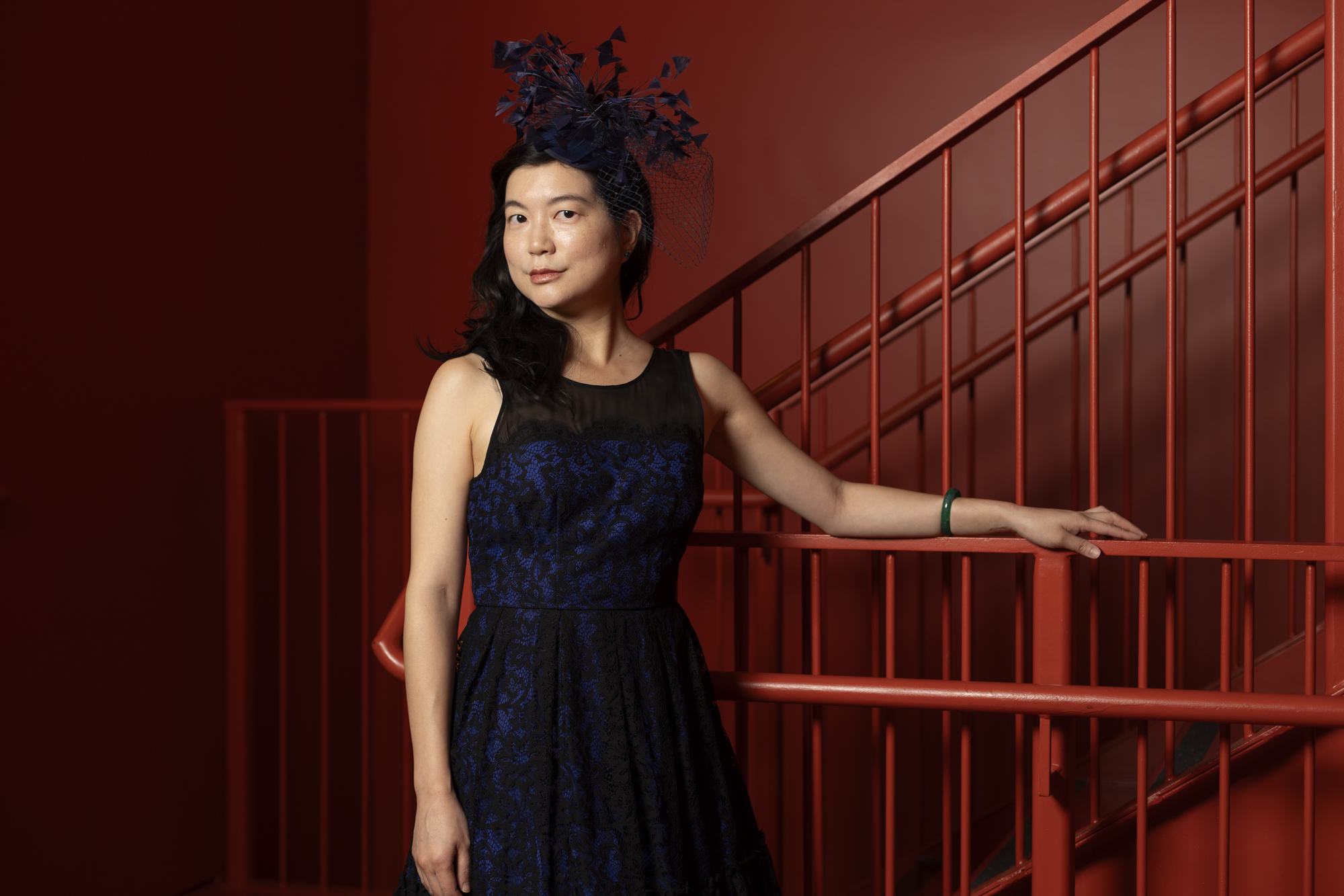 A woman in an elegant dark blue dress with matching floral hat.