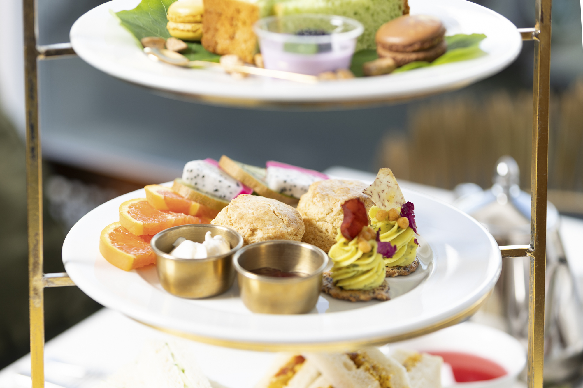 Three-tiered cake stand with an array of cakes, pastries and finger sandwiches.