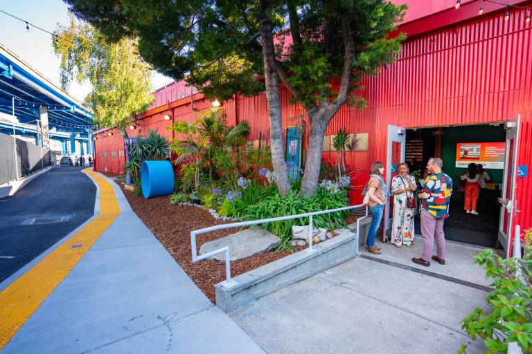doorway with people chatting in red-painted building beside freeway