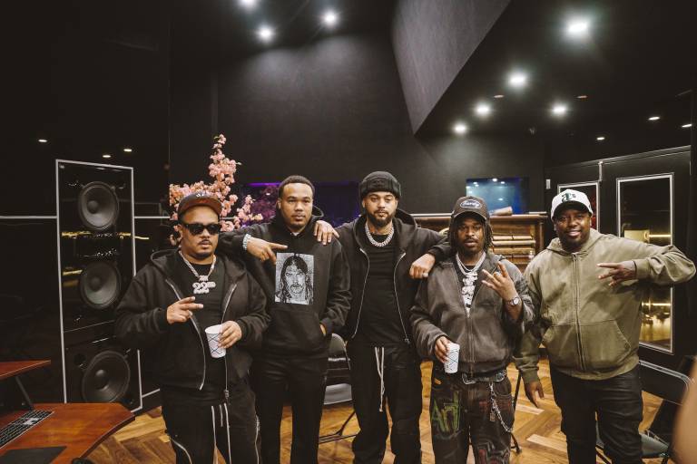 Five men African-American standing shoulder to shoulder in a music studio pose for a photo.