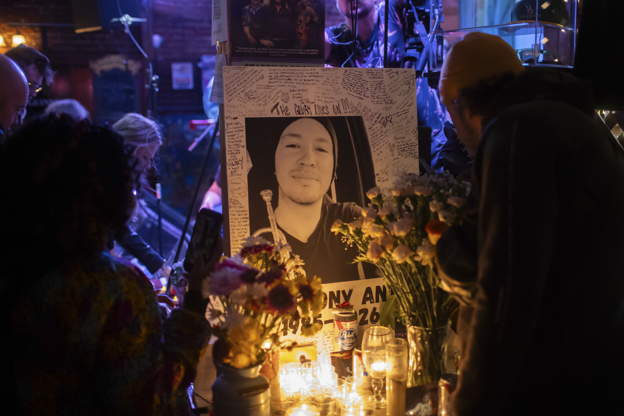 A photo of a man in a beanie is surrounded by candles