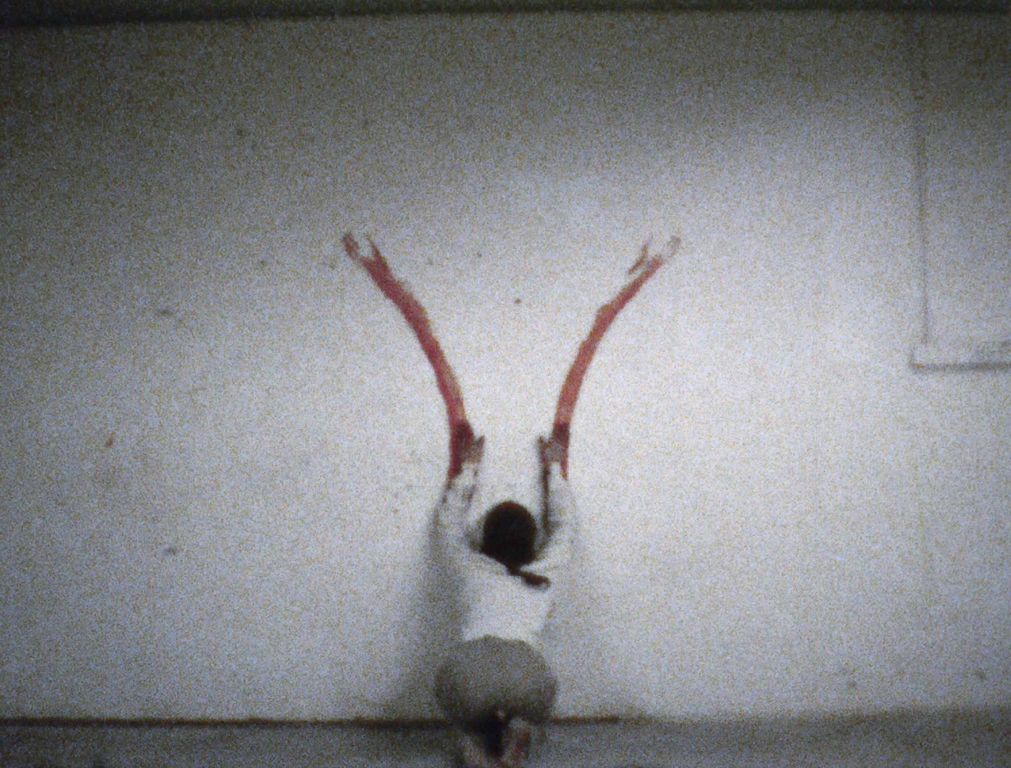 person kneels facing wall, hands at bottom of two red tracks above