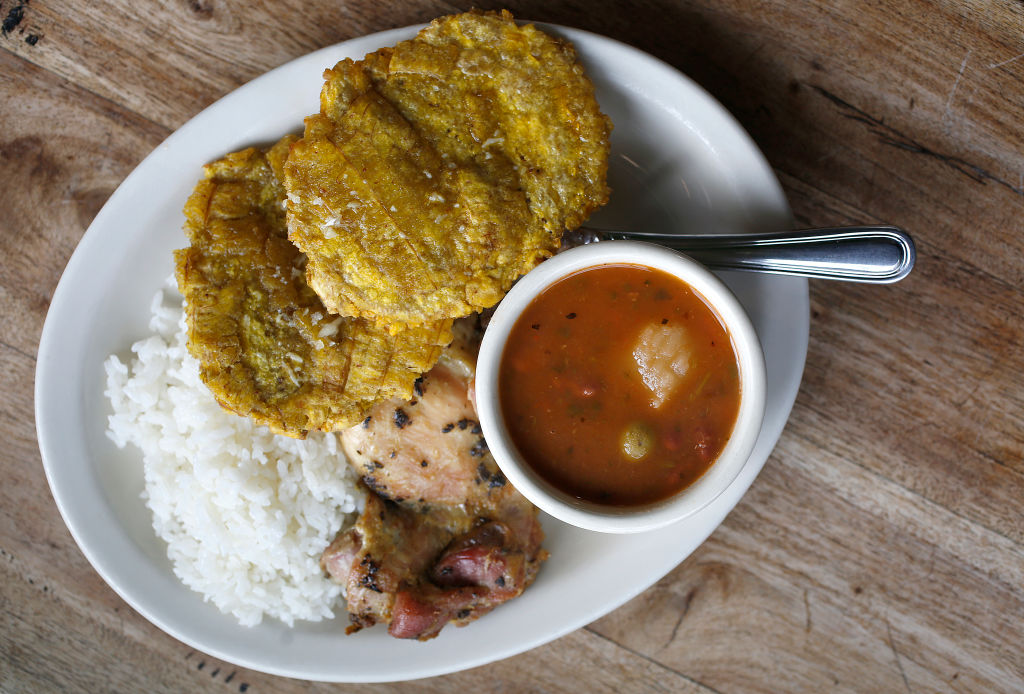 A plate of chicken, rice, plantains and soup
