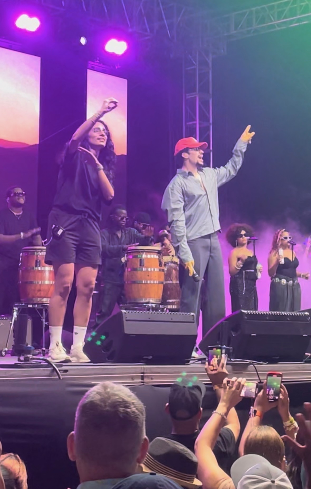 A sign language interpreter signs next to Bad Bunny on stage while he sings and gestures to the crowd.