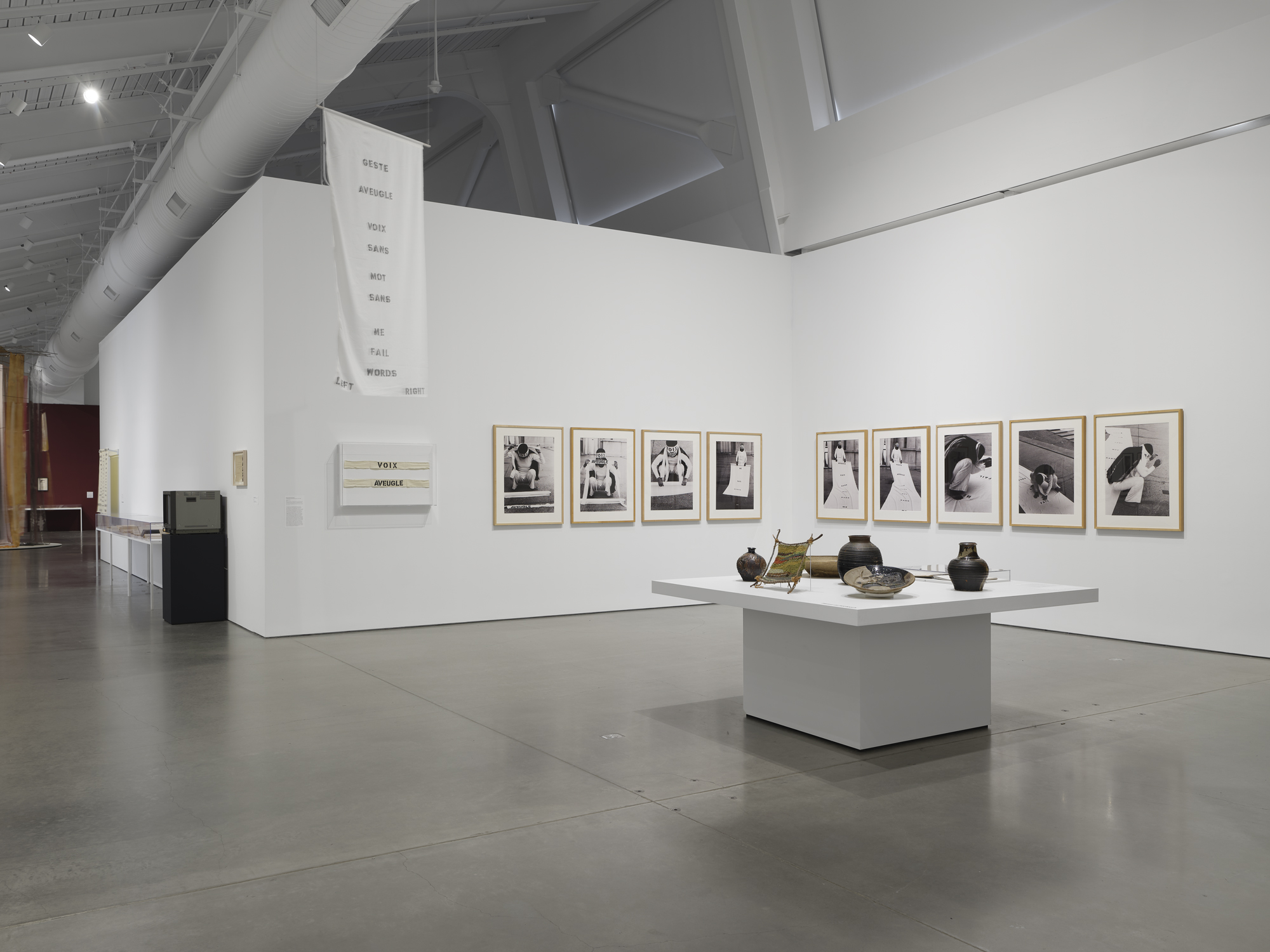 gallery view with framed black and white photographs and a table of ceramics