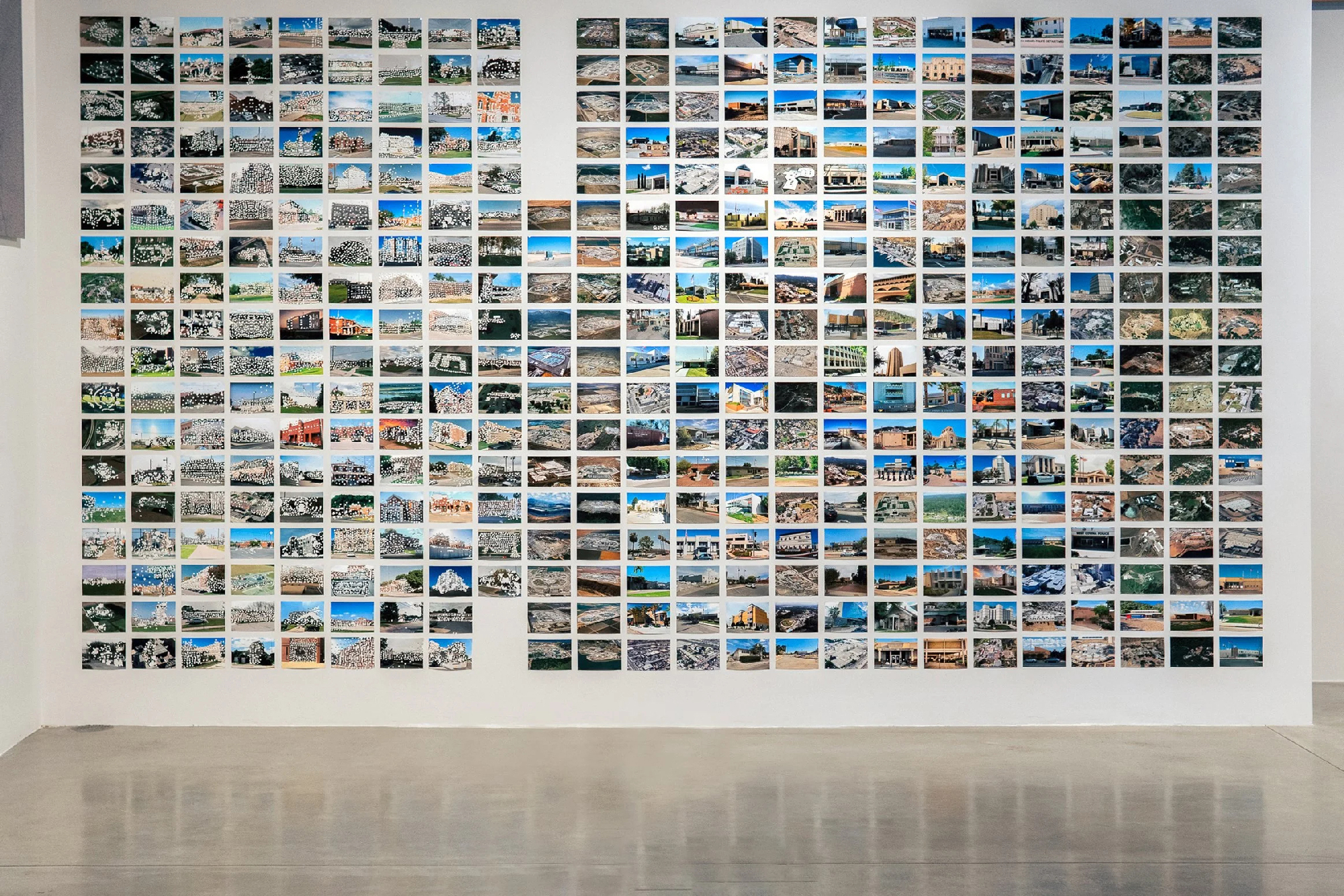 gallery wall covered with color photographs with punch holes