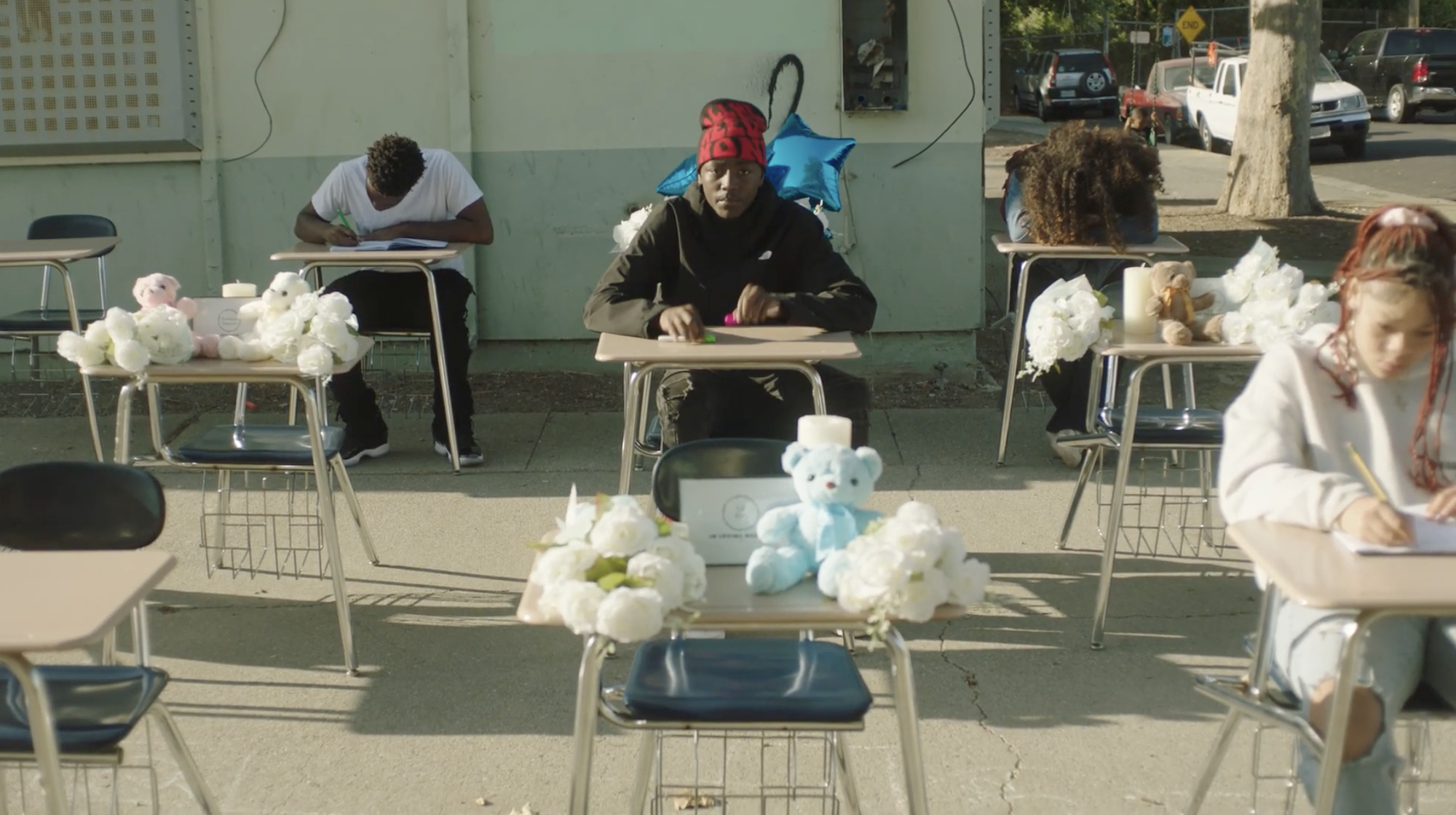 A young African-American student sits at a desk in a makeshift classroom. 