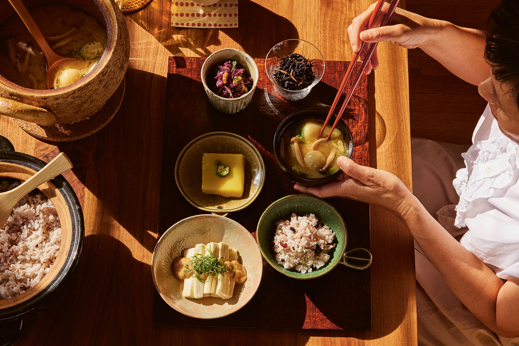 A woman seated in front of a spread of Japanese small plates.