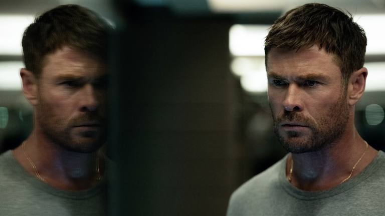 A handsome but grizzled looking white man frowns at his own reflection.