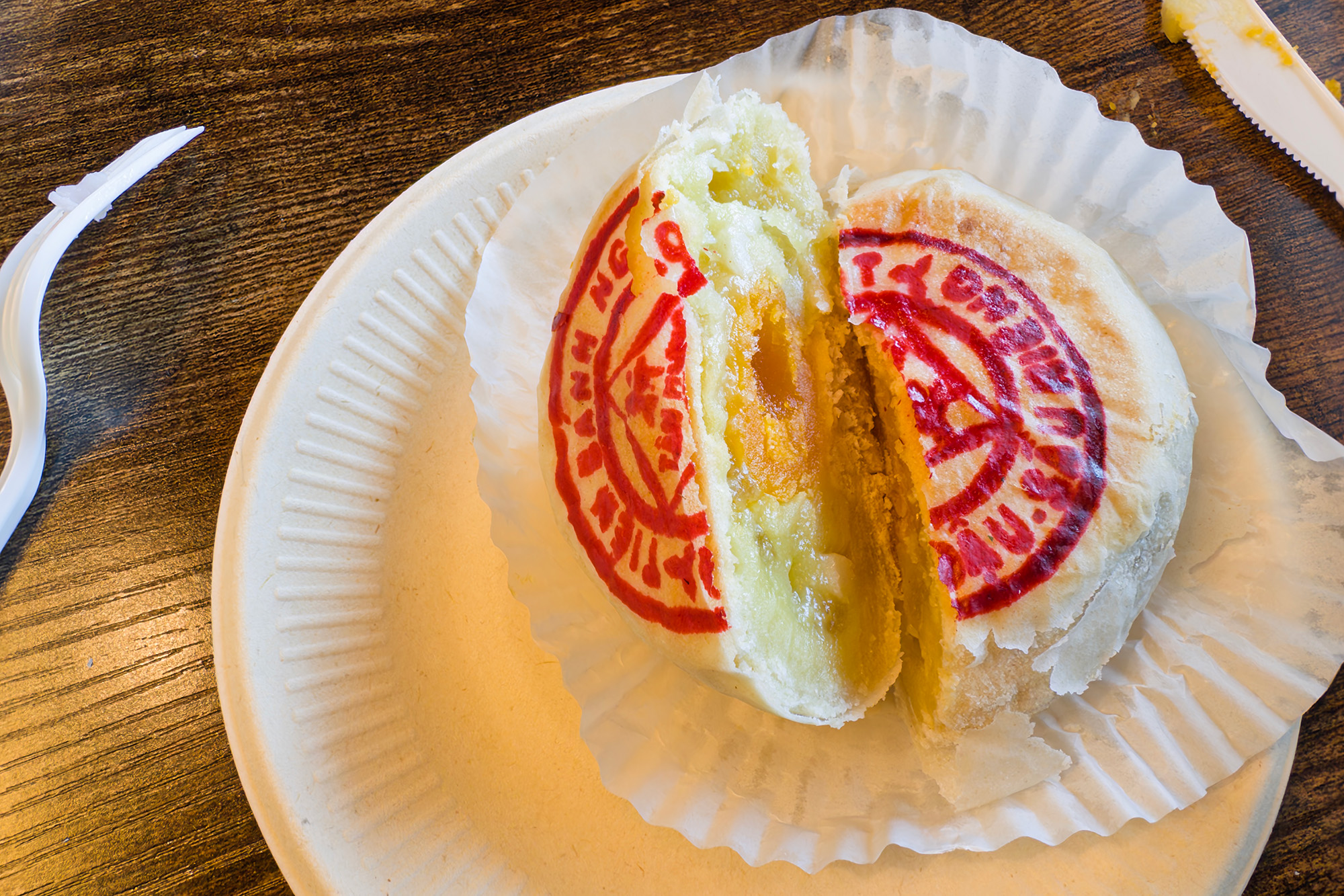 A flaky Asian pastry cut in half to reveal its durian and salted egg yolk filling.