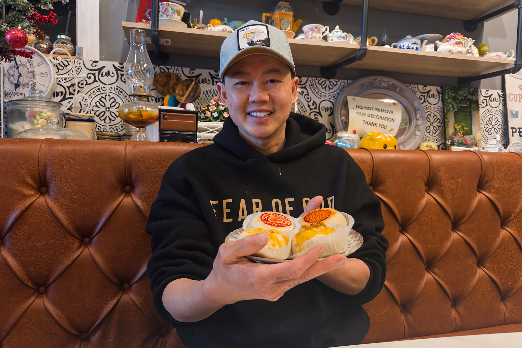A man in a baseball cap poses for a portrait while holding a plate of pastries.