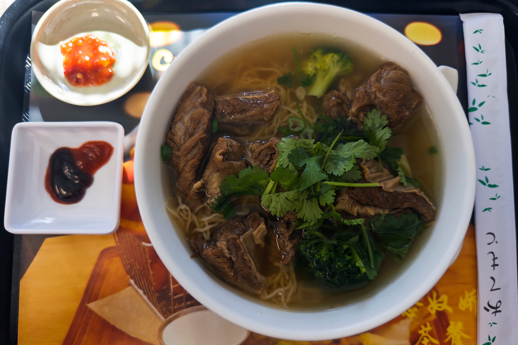 Bowl of beef noodle soup on a tray.