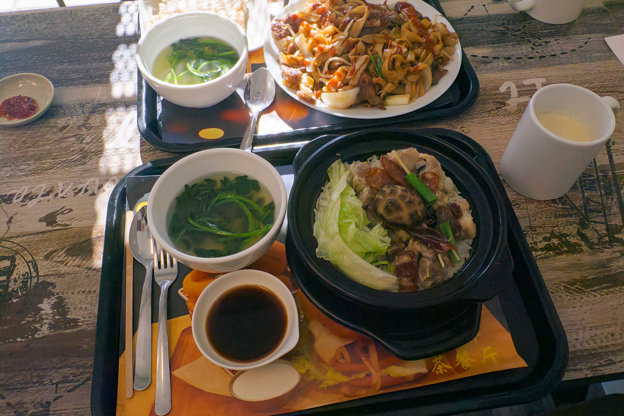 Claypot rice and a plate of beef chow fun on cafeteria-style trays.