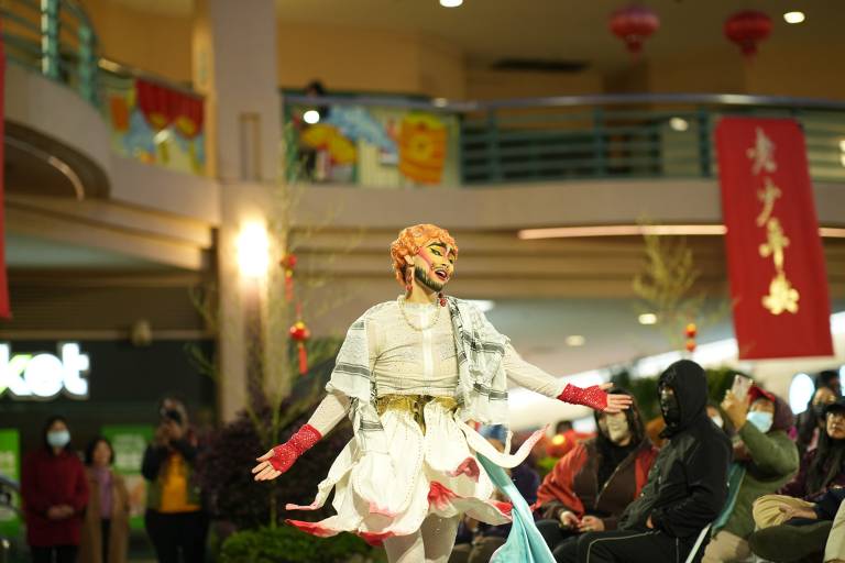 A drag king performer dances in a crowded plaza.
