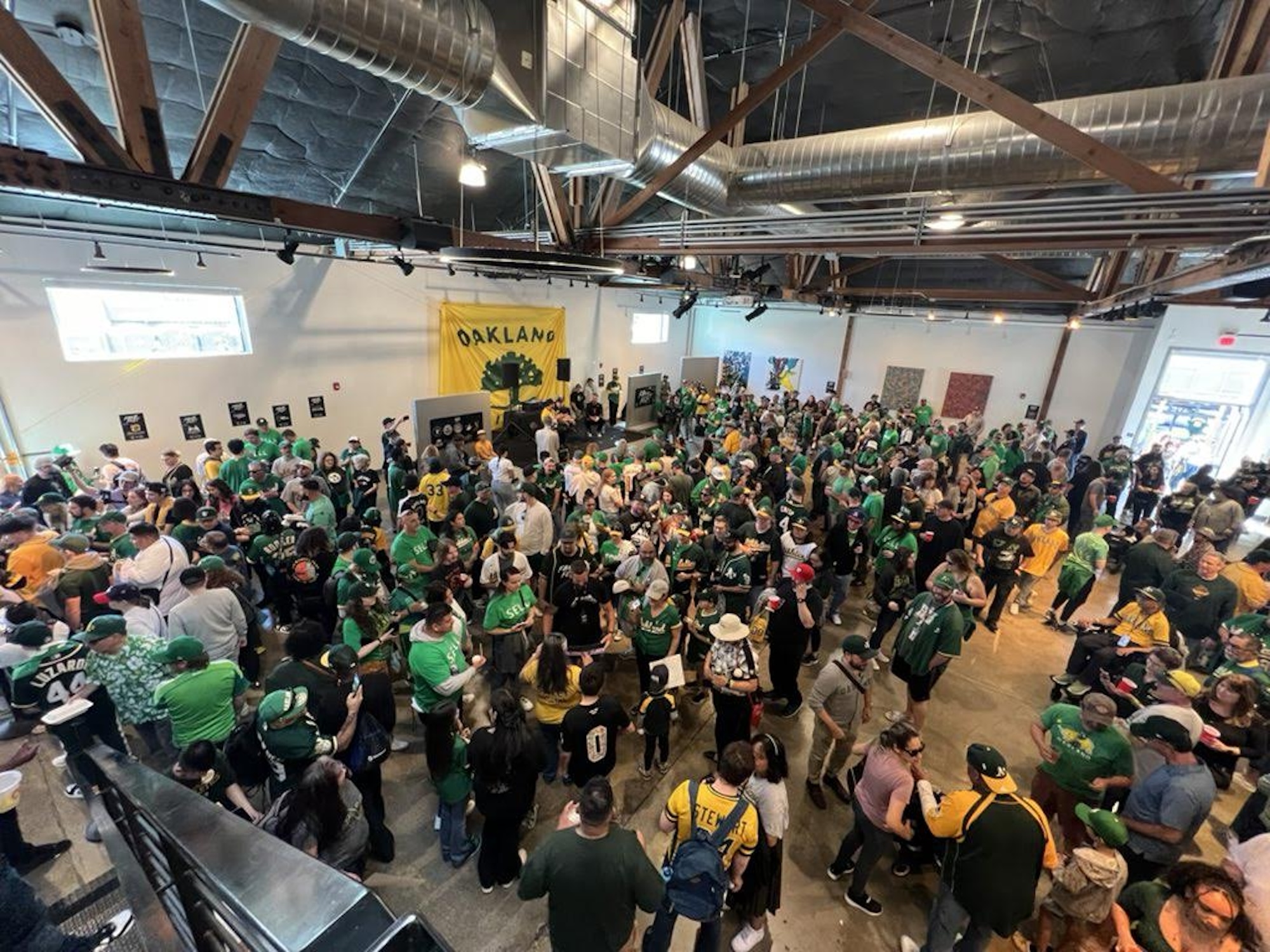 An overhead view of a large group of sports fans, mostly wearing green, gathered inside of a building.