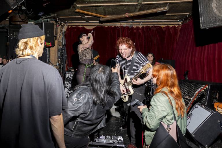 A young punk band plays on a dive bar's stage.