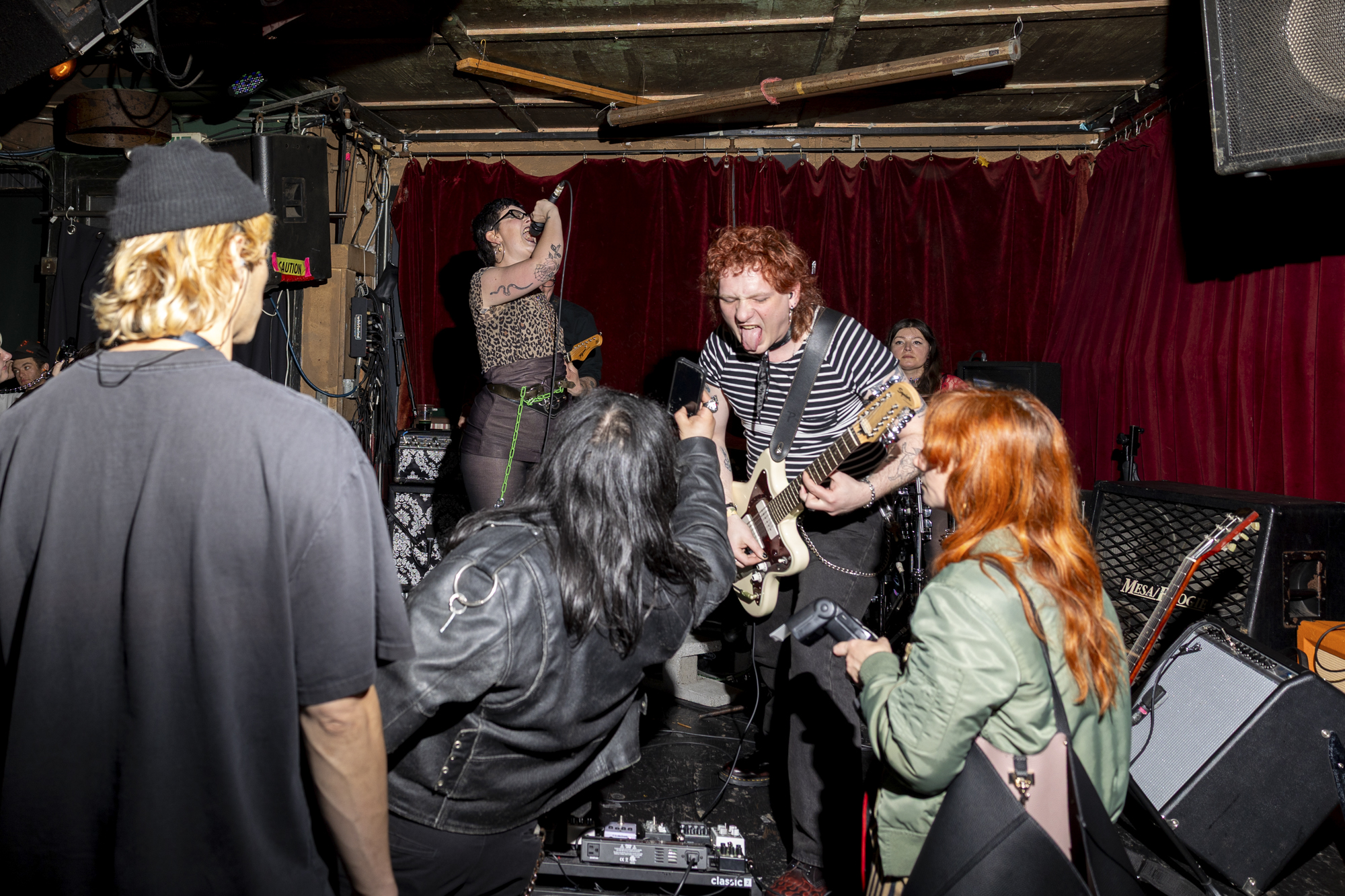 A young punk band plays on a dive bar's stage.