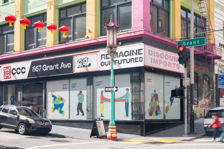 corner building with illustrations in windows, red lanterns hanging across street