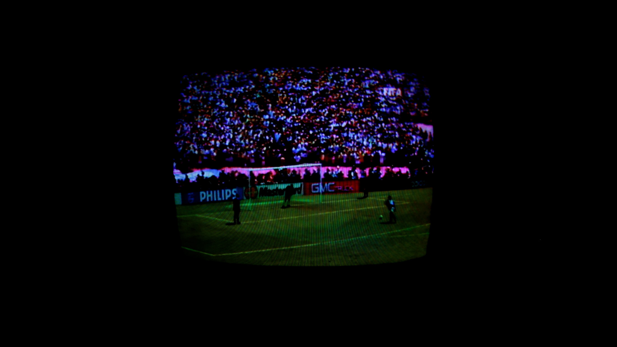 tv screen showing soccer game in darkened space