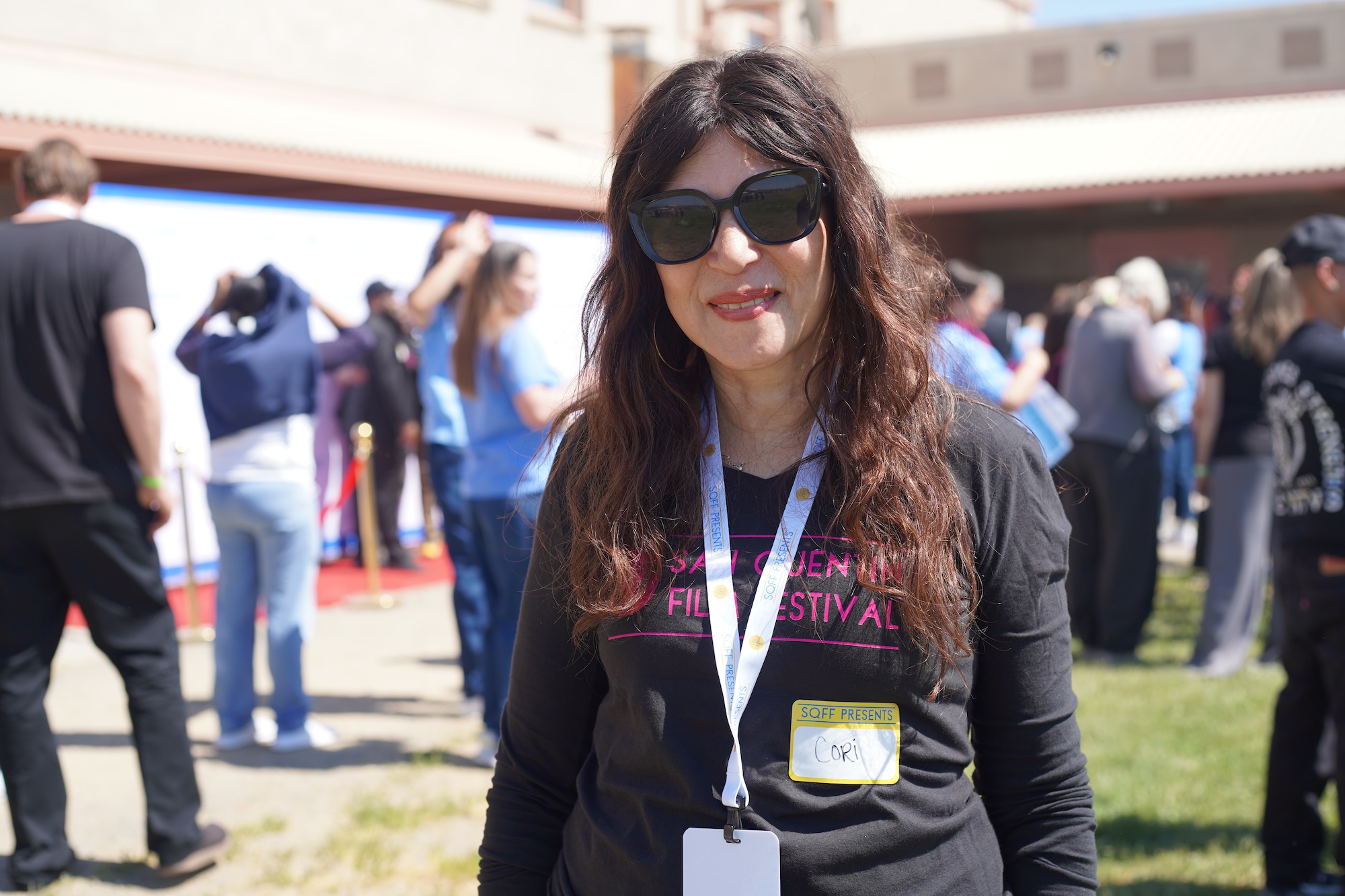 A woman in dark sunglasses poses for a photo. 