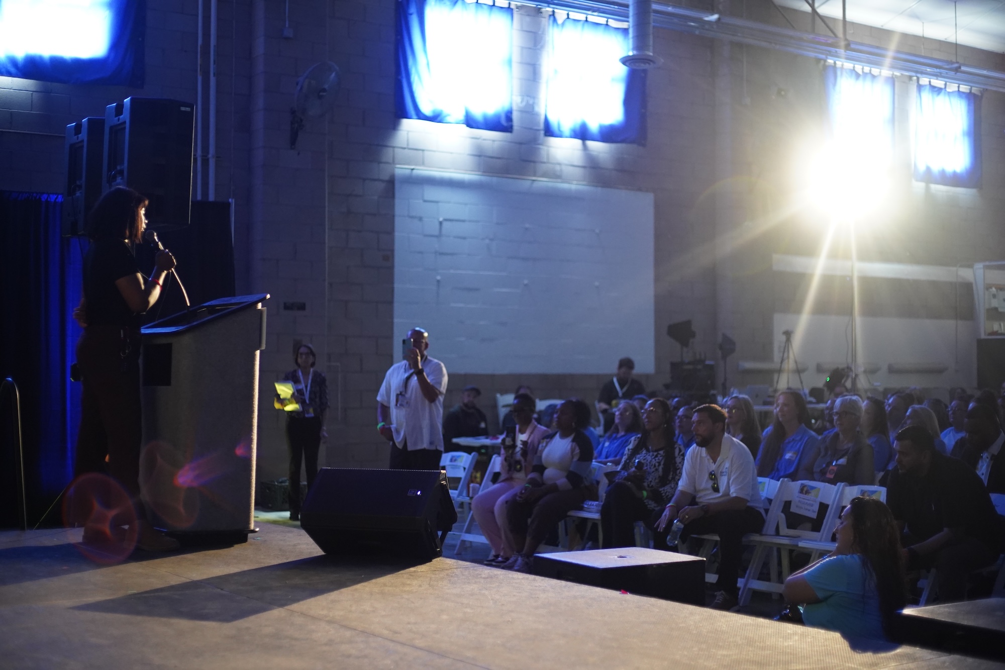 A woman standing on stage while speaking into a microphone. 