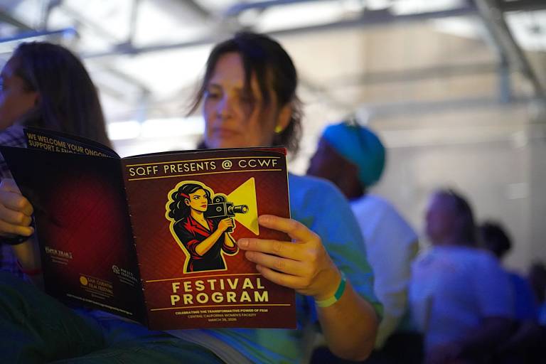 A woman reads a printed program for the San Quentin Film Festival at California Central Women's Facility.