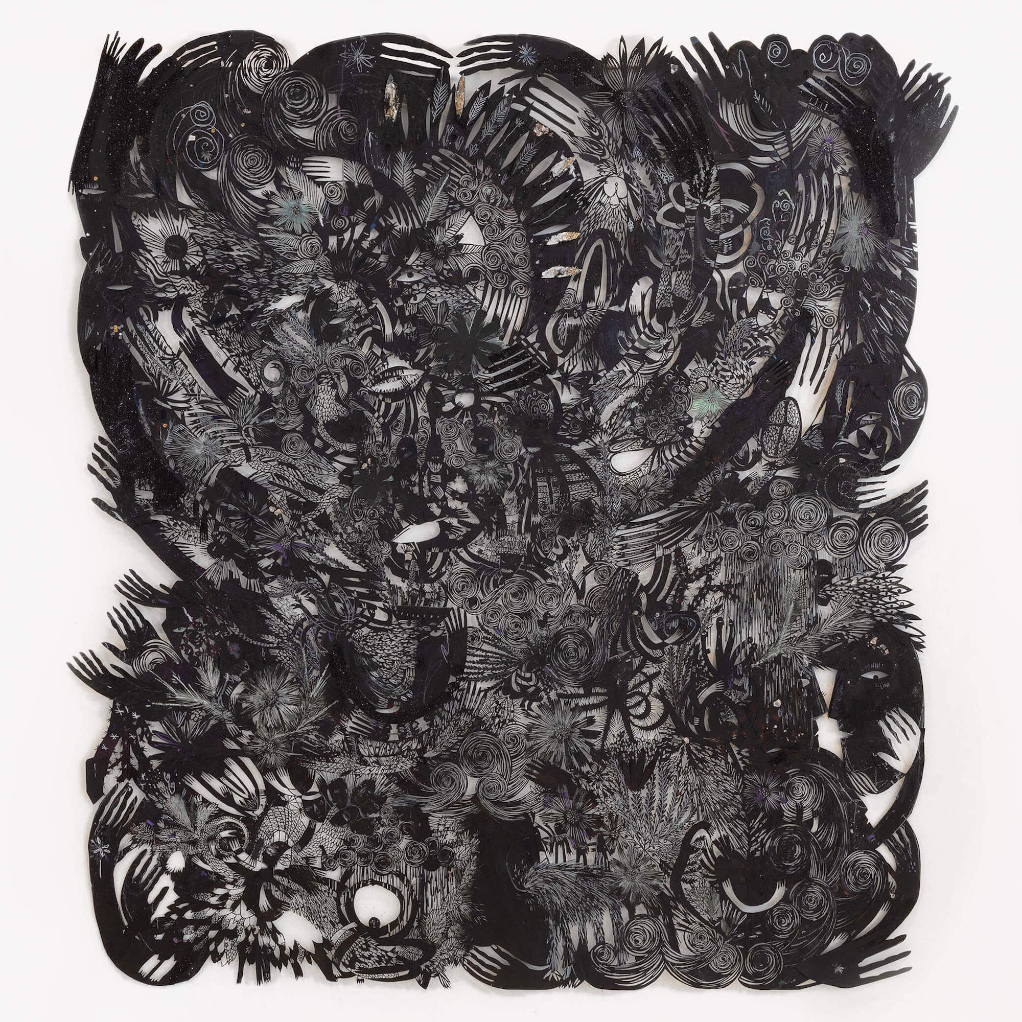 black paper with cut-in imagery of swirls, hands, plants, etc.
