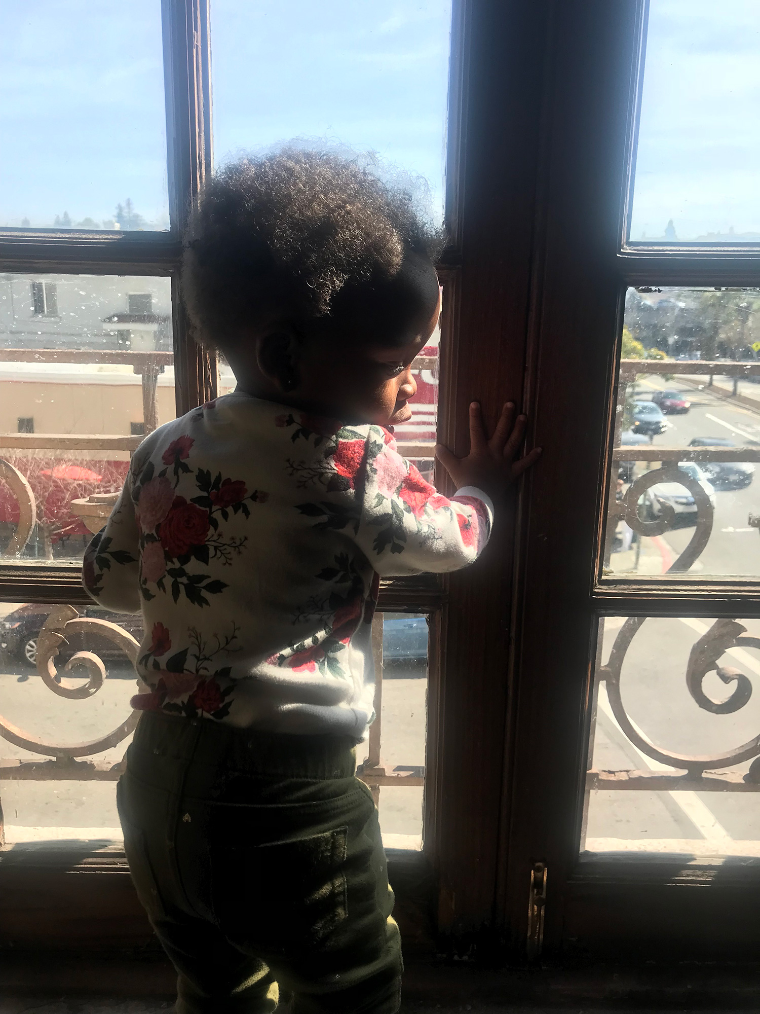 A small child standing by a window.