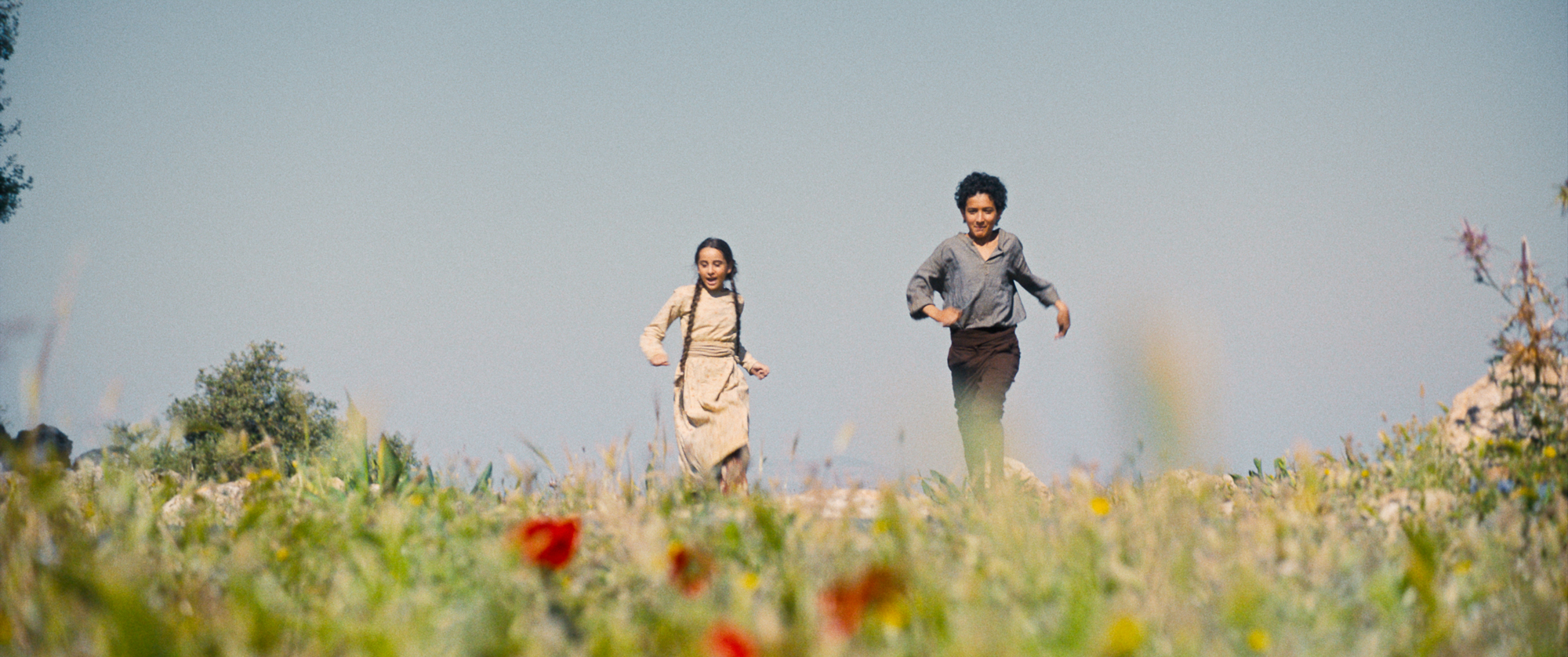 two children run through flowering field