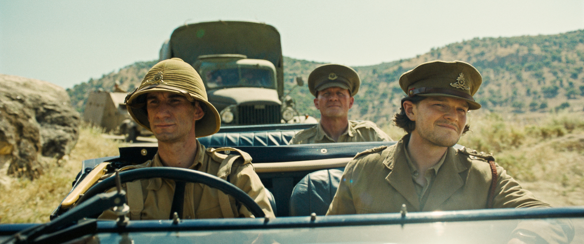 three military men drive in open-topped car