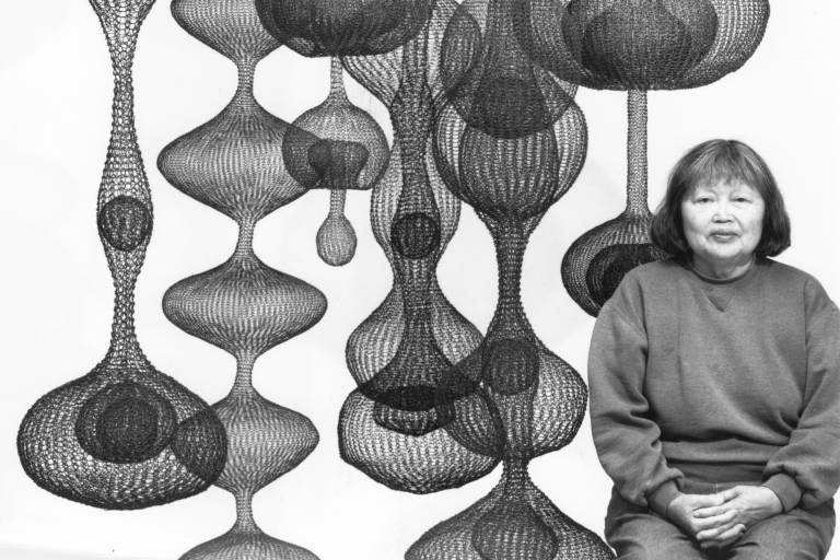 woman next to globular mesh hanging sculptures