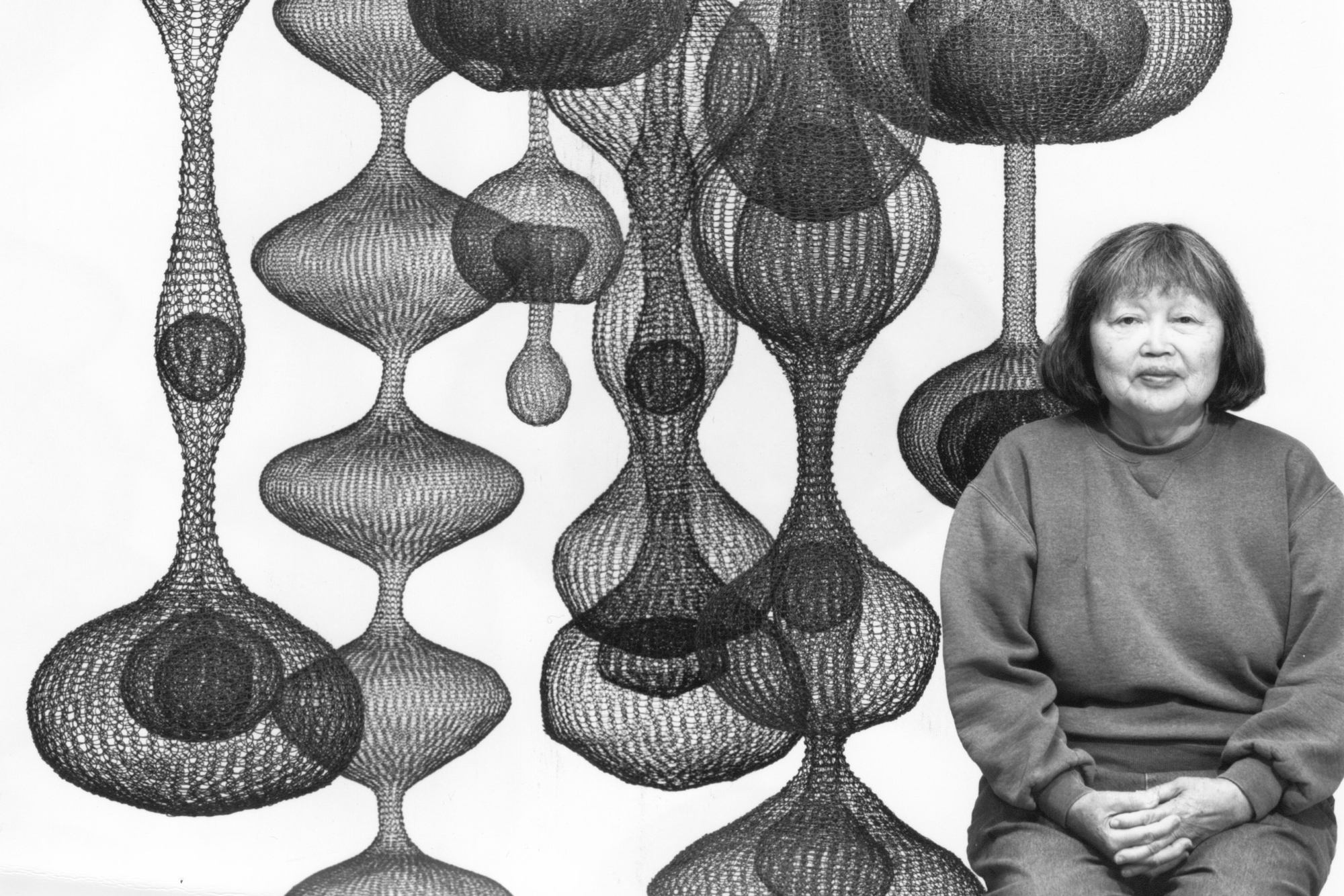 woman next to globular mesh hanging sculptures