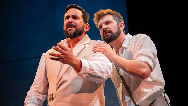 Two men look off to the left, dramatically, in white clothing and questionable haircuts