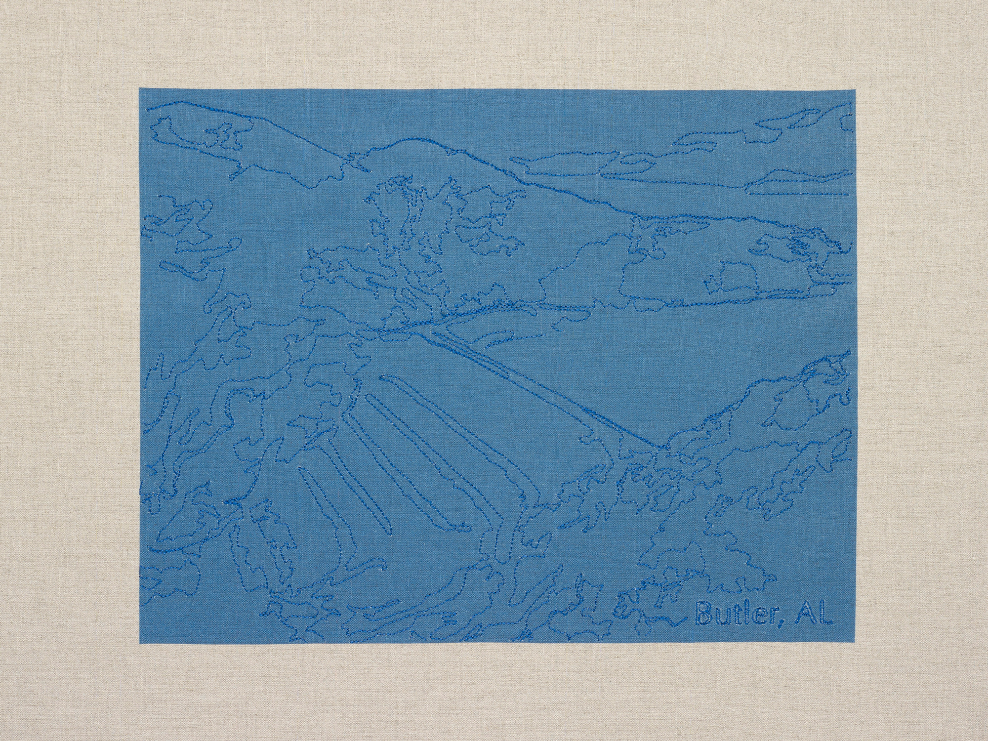 blue embroidery on blue field to trace image of a dam in landscape