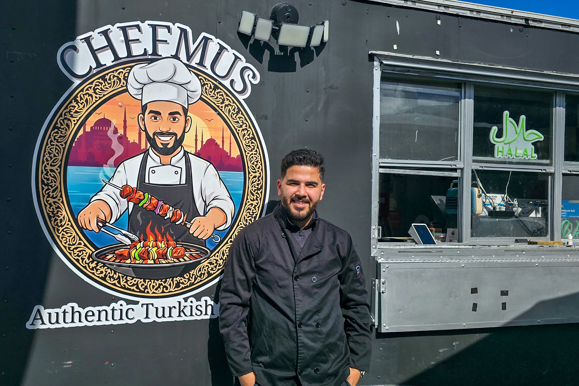 A man poses in front of a food truck.