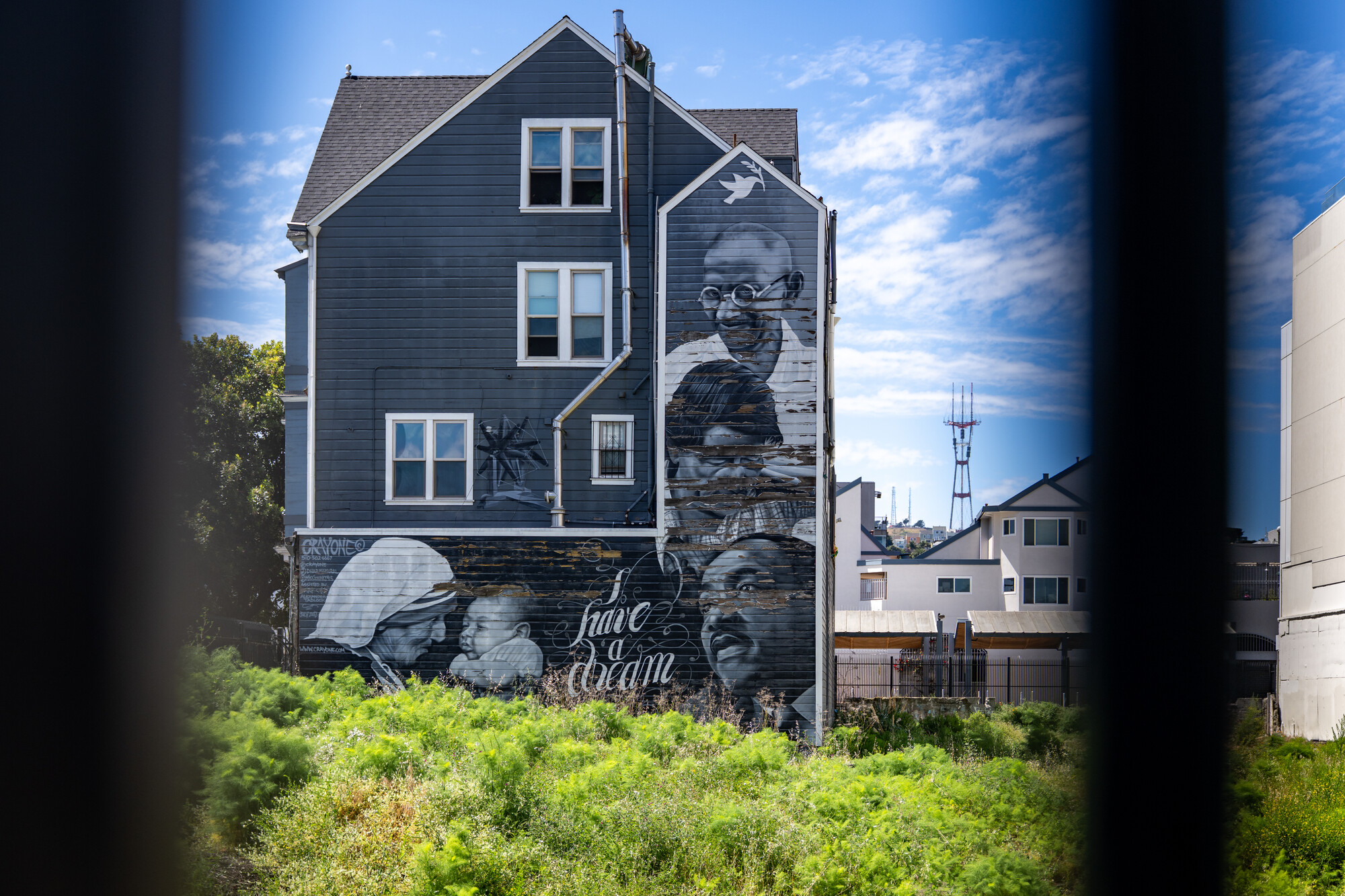 gray-toned mural with civil rights leaders seen through fencing