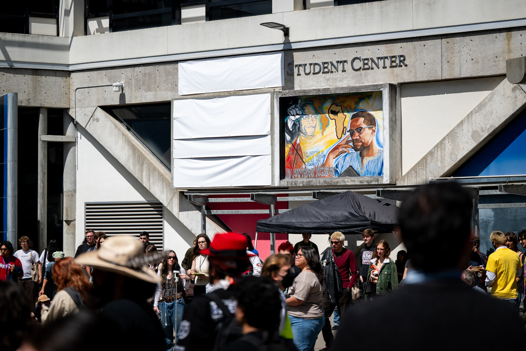 white banner over building name and part of mural, students below