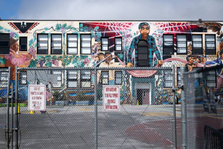 view of schoolyard through chain link fence with mural painted on building