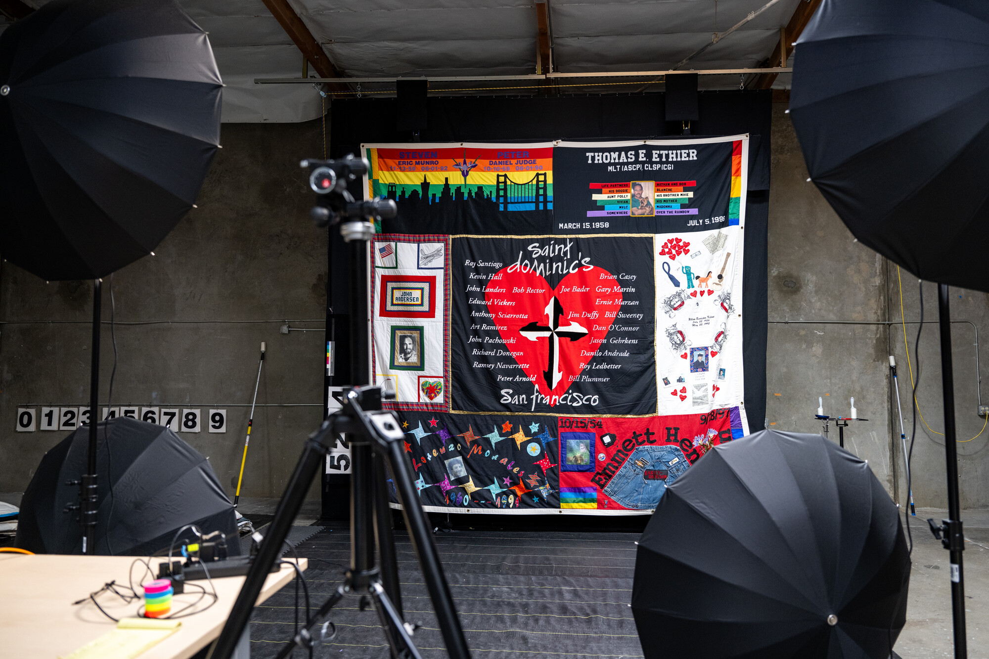photo flash umbrellas surround a large-scale quilt hanging on wall