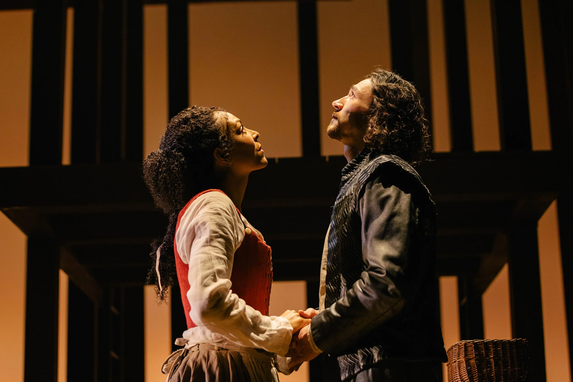 A man in blue and a woman with a flower crown look upward