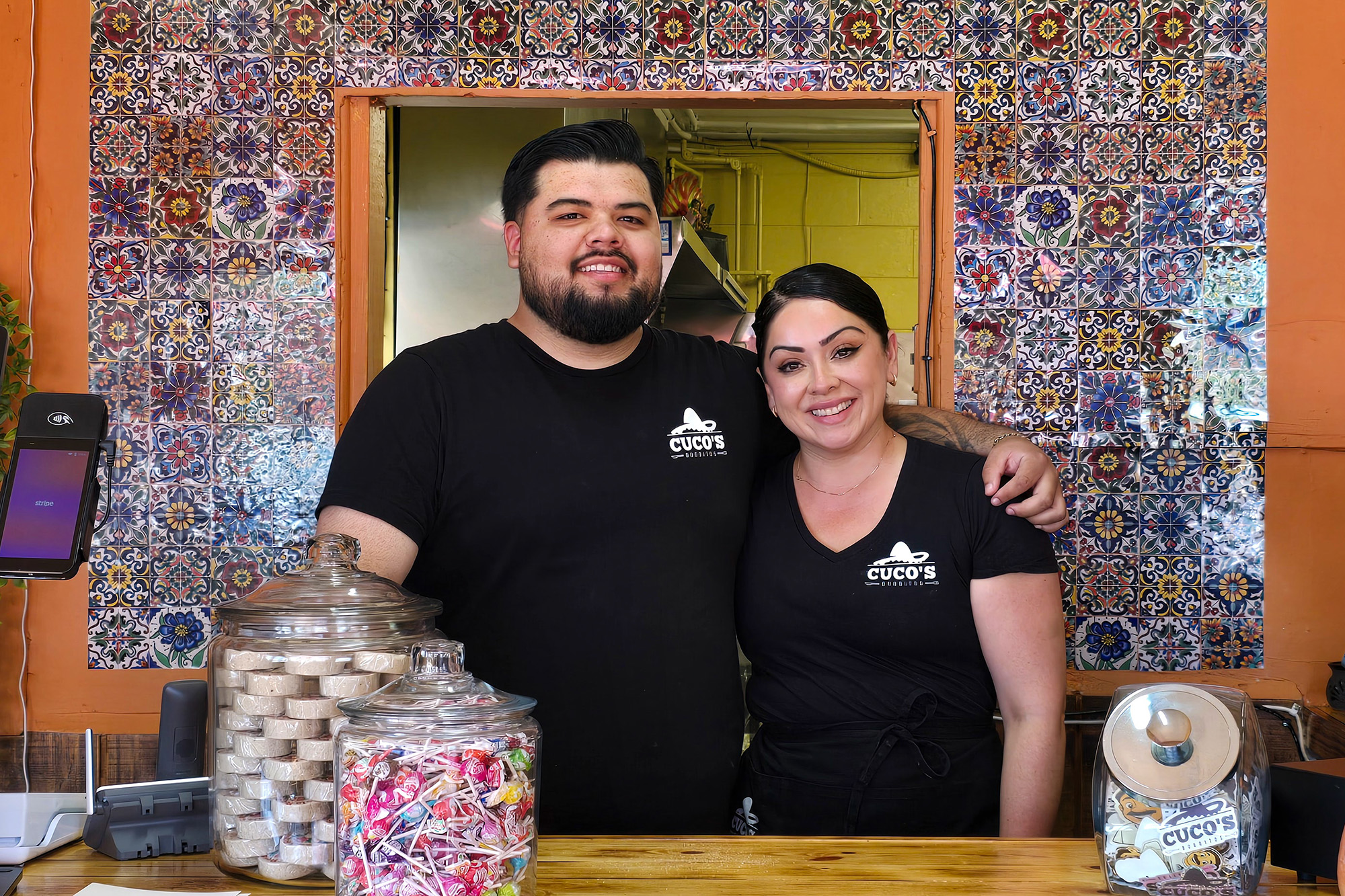 A man and woman pose for a portrait inside a restaurant.