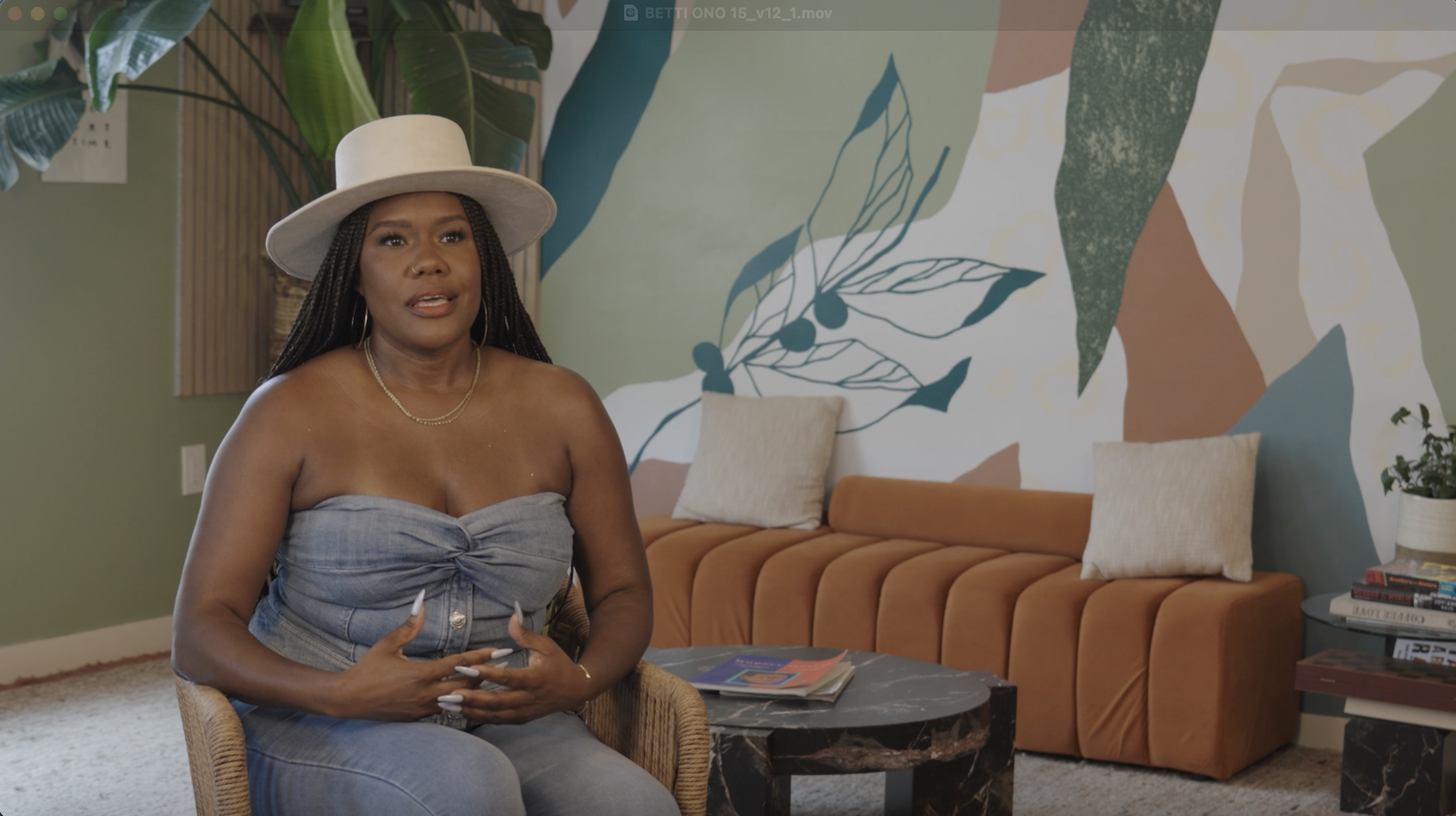 An African American woman in a hat sitting while being interviewed. 
